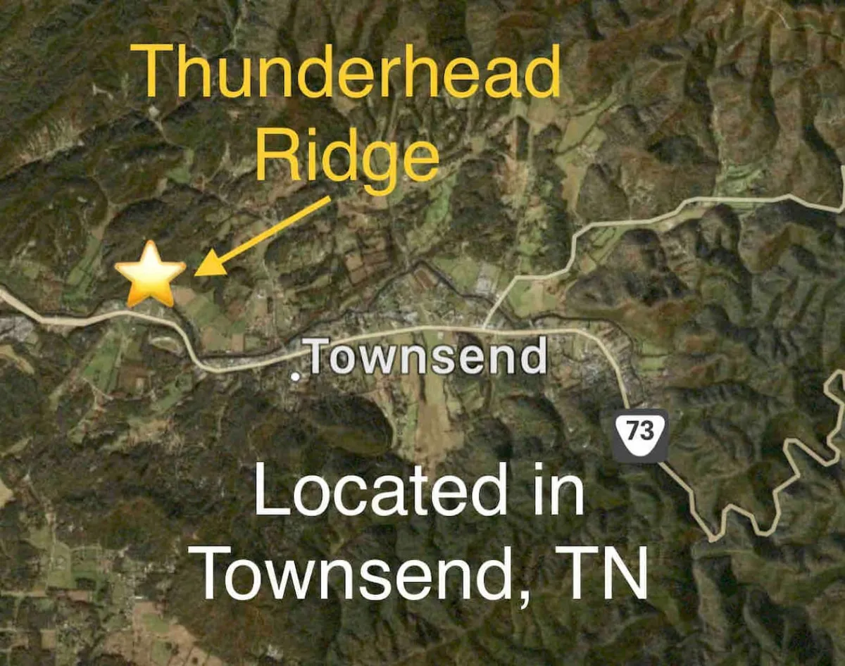 A sweeping view from Thunderhead Ridge overlooking the valley below, with the town of Townsend and the rolling hills of the Smoky Mountains stretching to the horizon. The landscape features lush greenery and hints at endless outdoor adventures such as hiking, wildlife watching, and stargazing.