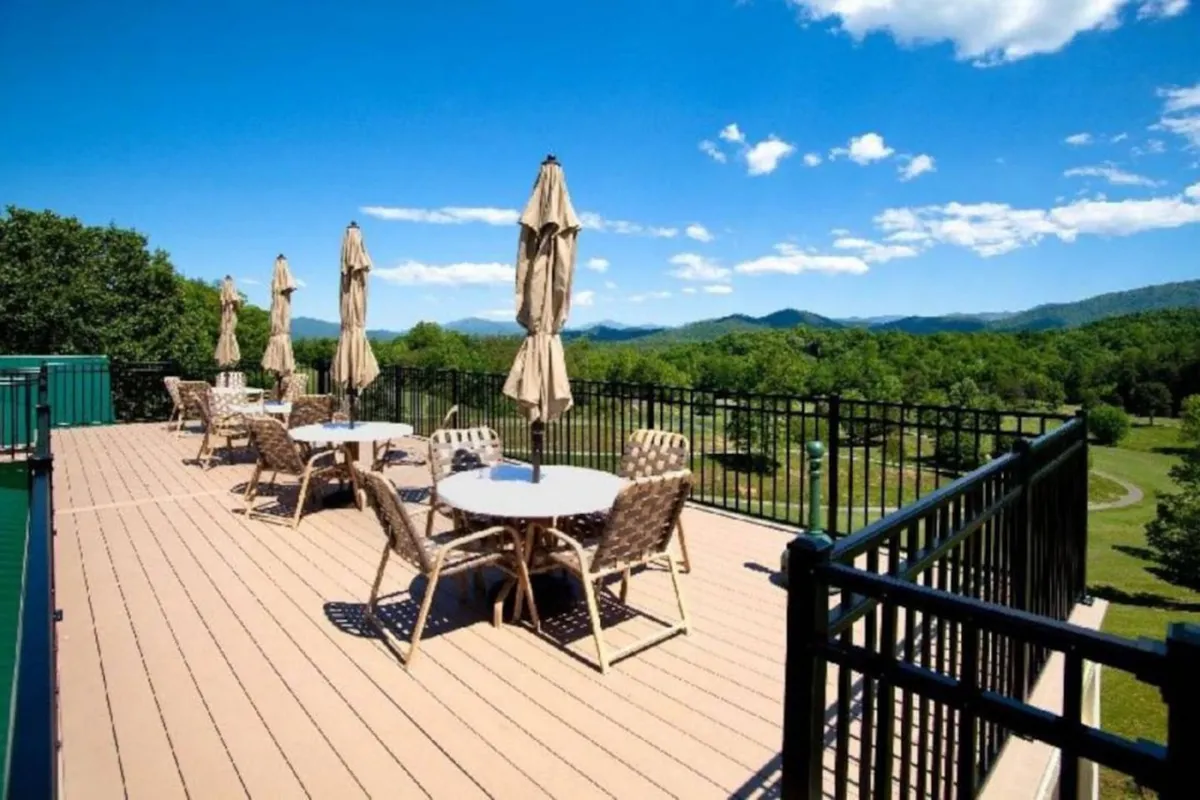 This exterior image features inviting outdoor seating beneath umbrellas, set against a stunning mountain backdrop. The scene captures the peaceful ambiance of the property, with ample space for families to relax, socialize, and enjoy the views together. The open layout and scenic surroundings emphasize outdoor enjoyment and togetherness.